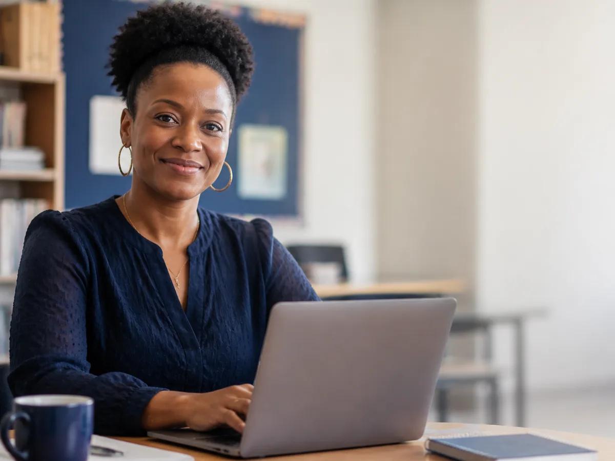 A teacher at a desk in an empty classroom at the end of the day
